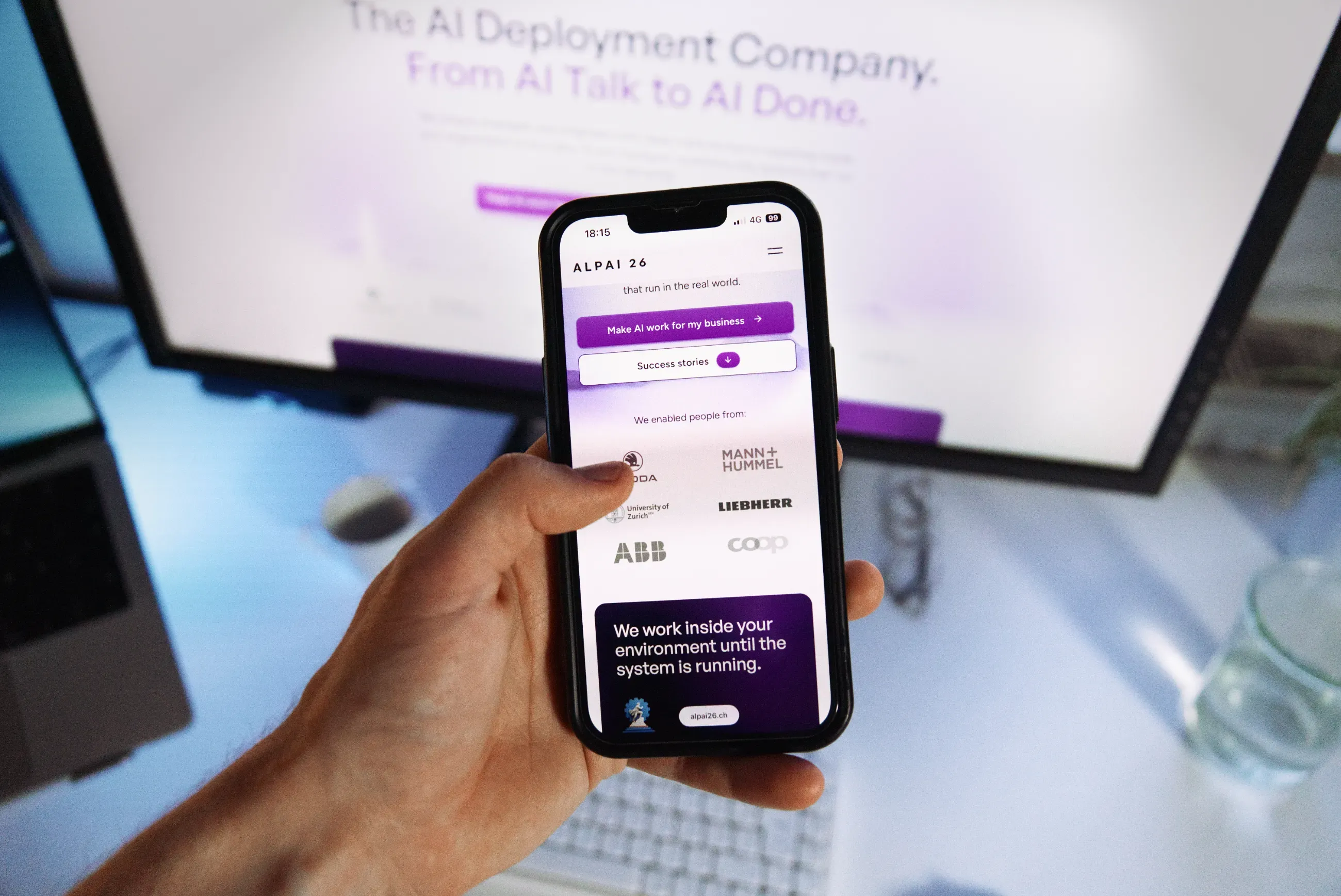 Die Website von Alpai26, gebaut von Studio Erlach, auf dem Smartphone in der Hand, dahinter am Bildschirm